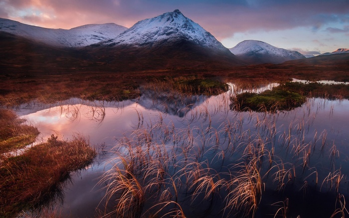Snow-capped mountains reflected in a calm lake at sunrise