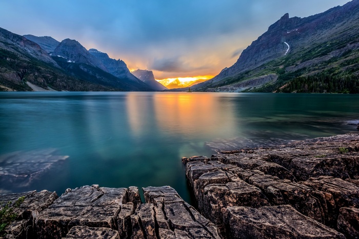 Sunset over a mountain lake with rocky foreground