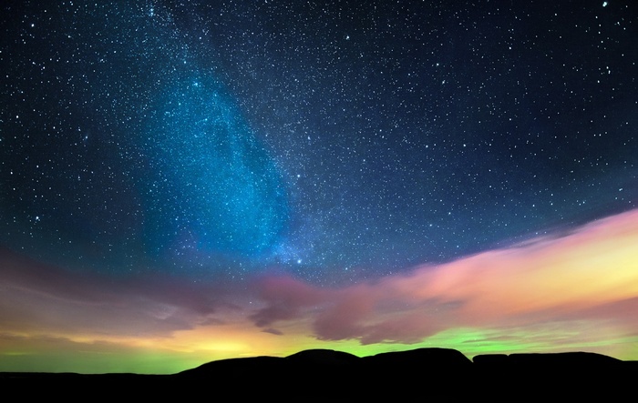 Night sky with stars and aurora over silhouette landscape