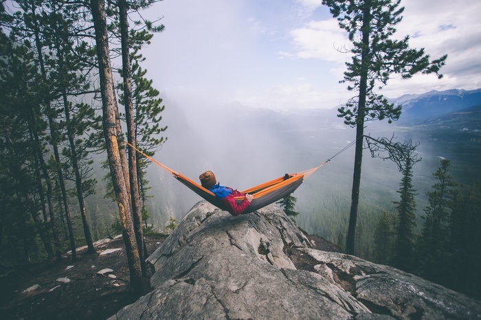 Person relaxing in a hammock on a cliff edge
