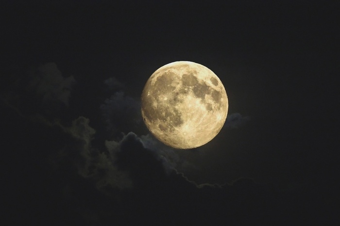 Full Moon partially obscured by clouds at night