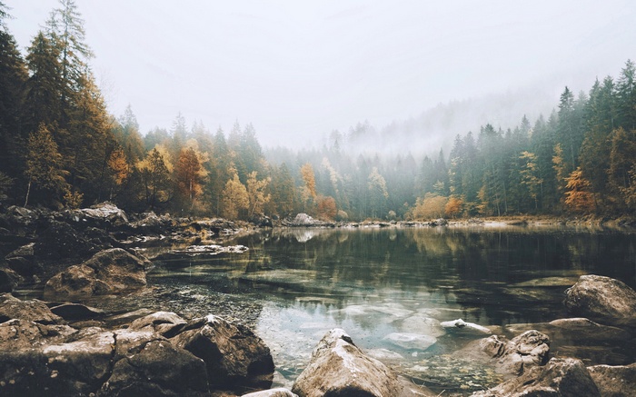 Misty lake surrounded by autumn trees and rocks