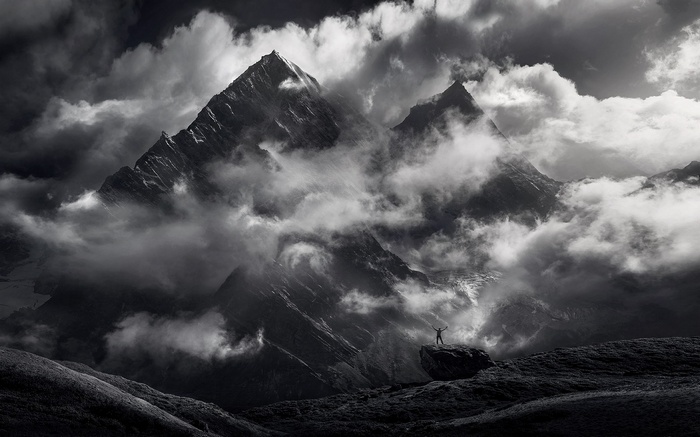 Monochrome mountain landscape with clouds and a lone figure