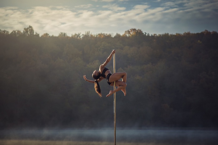 Woman performing pole dance on a misty lake