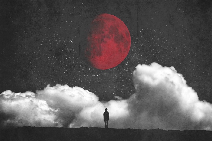 Silhouette of a person under a red moon