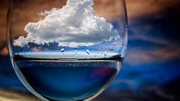 Clouds and sky reflected in a glass of water