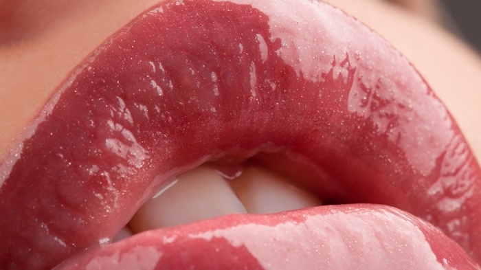 Close-up of glossy pink lips with teeth visible