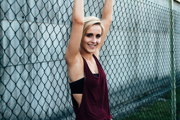 Woman with blonde hair smiling by a fence