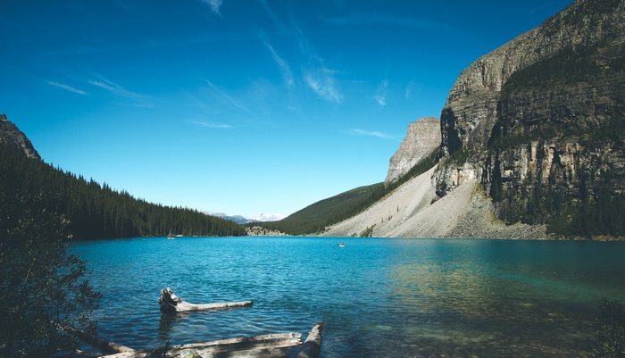 Turquoise lake surrounded by pine forest and rocky mountains