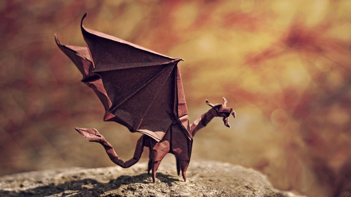 Brown origami dragon with wings on a stone