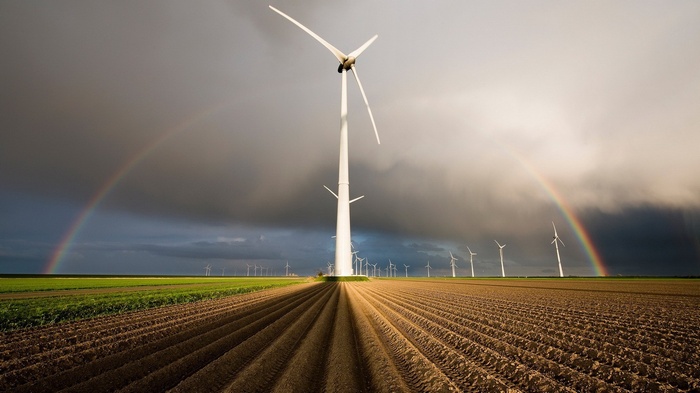 Wind turbines and rainbows over a plowed field