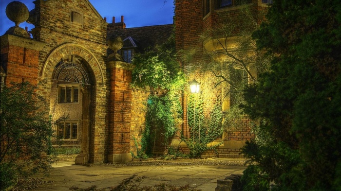 Old brick building with archway and lantern at dusk