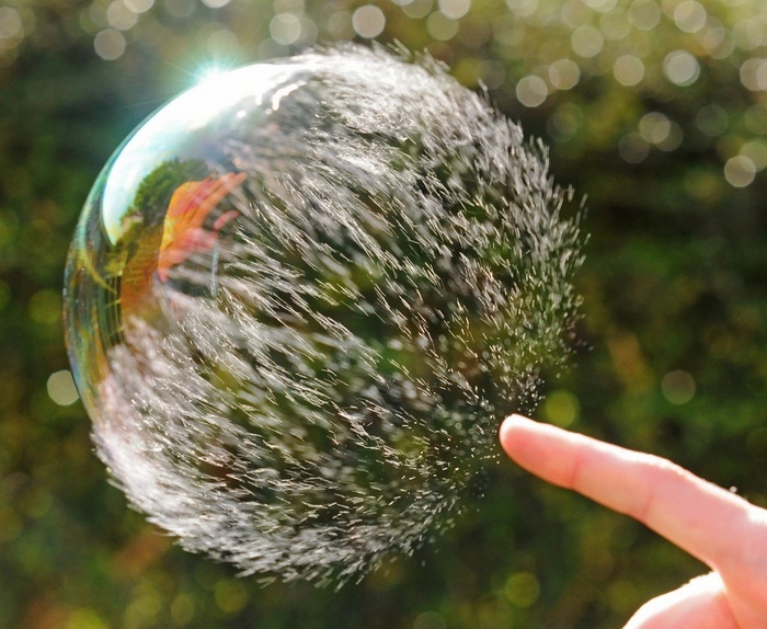 A finger about to pop a water bubble