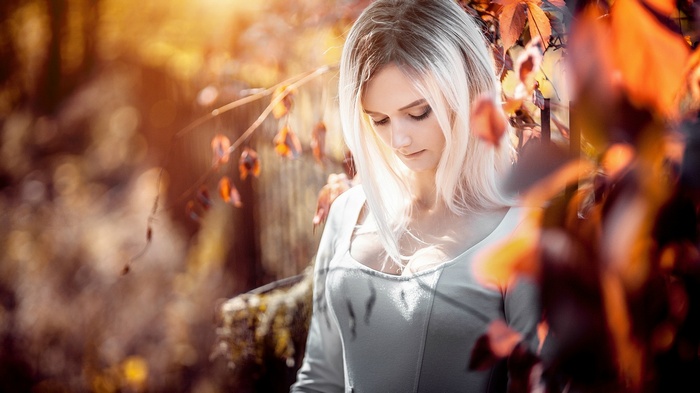 Autumn Lynn in a white dress surrounded by fall leaves