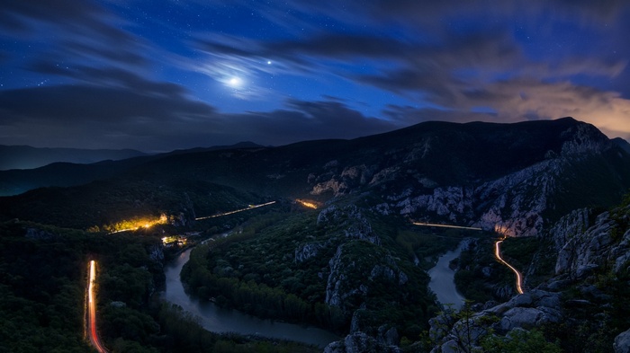 Night landscape of a river valley with mountains and stars