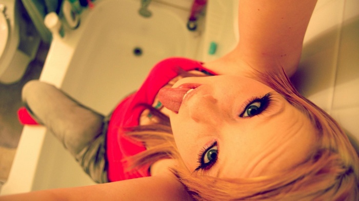 Girl with dyed hair sticking out her tongue in a bathtub