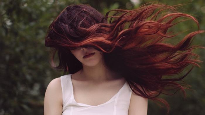 Woman with long red hair blowing in the wind outdoors