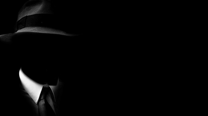 Man in fedora and suit in darkness