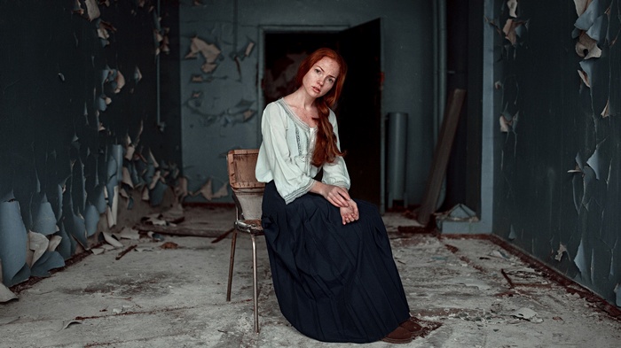 Oksana Butovskaya sitting in a chair in ruins