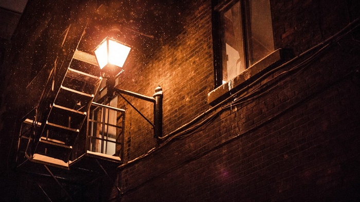 Snow falling on a street light and fire escape