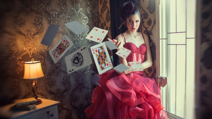 Woman in red dress throwing playing cards