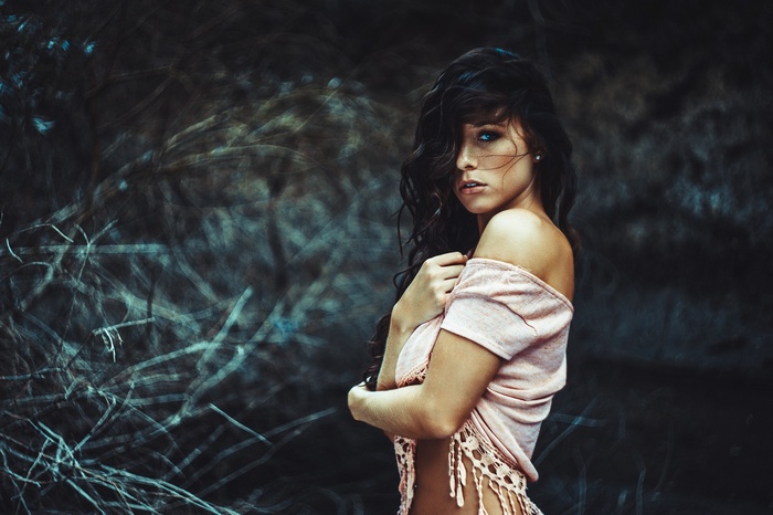Woman with wavy hair and bare shoulders outdoors