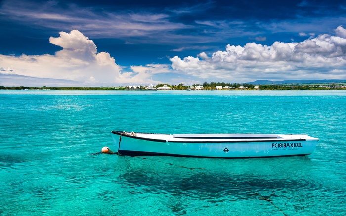 A white boat floats on turquoise water near Mauritius