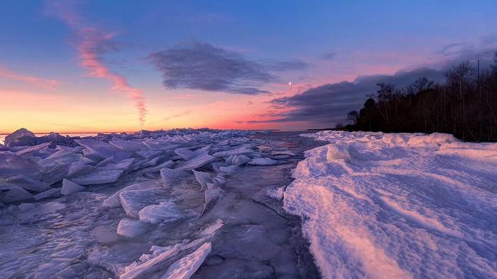 Frozen lake at sunset with ice formations and clouds