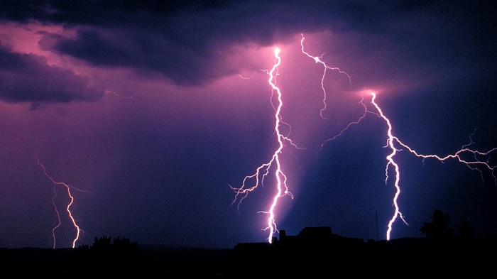 Lightning strikes over silhouetted landscape at night