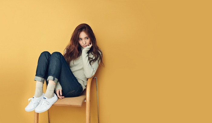 Krystal sitting on a chair against a yellow background