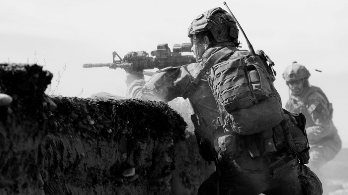 Soldiers in tactical gear aiming rifles in a dusty environment
