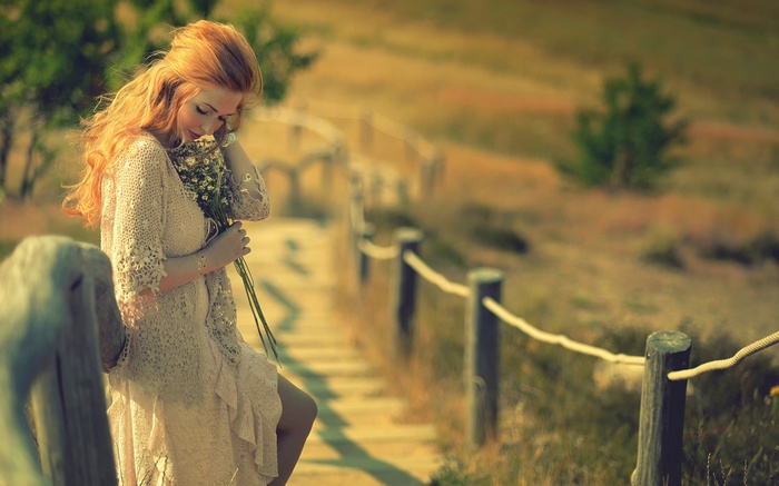 Redhead woman with flowers on a wooden path