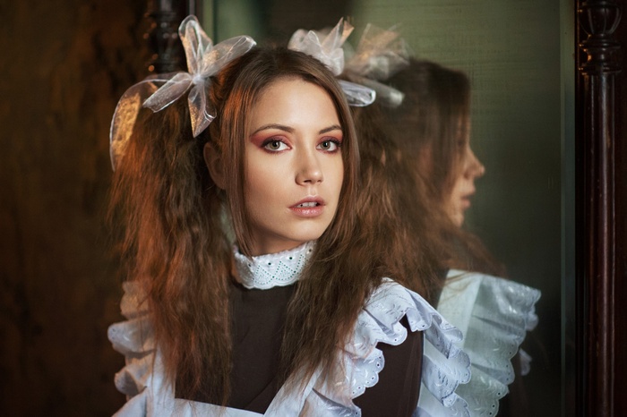 Ksenia Kokoreva in a maid outfit reflected in a mirror