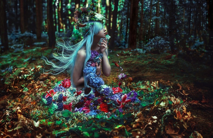 Fantasy girl with horns and flowers in forest