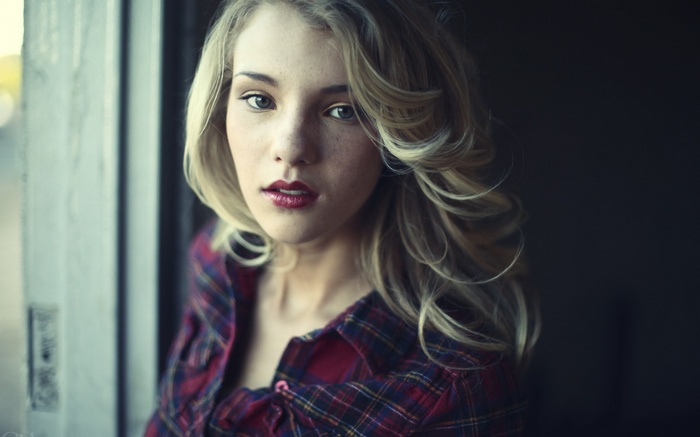 Portrait of a blonde woman with freckles wearing a plaid shirt
