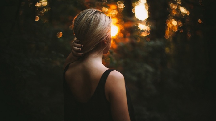 Woman with blonde hair in the forest at sunset
