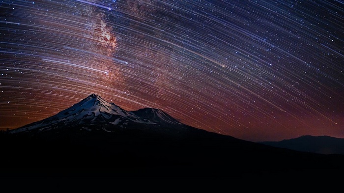 Star trails over a snowy mountain peak in California