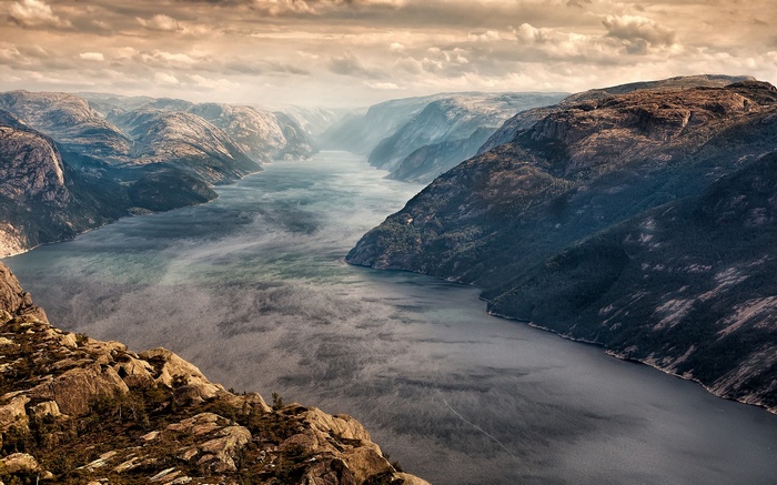 Fjord landscape with mountains and mist at sunset