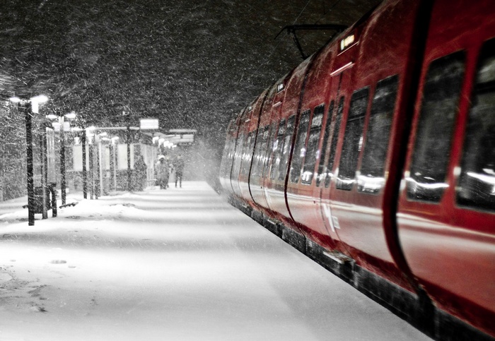 Red train at a snowy station at night