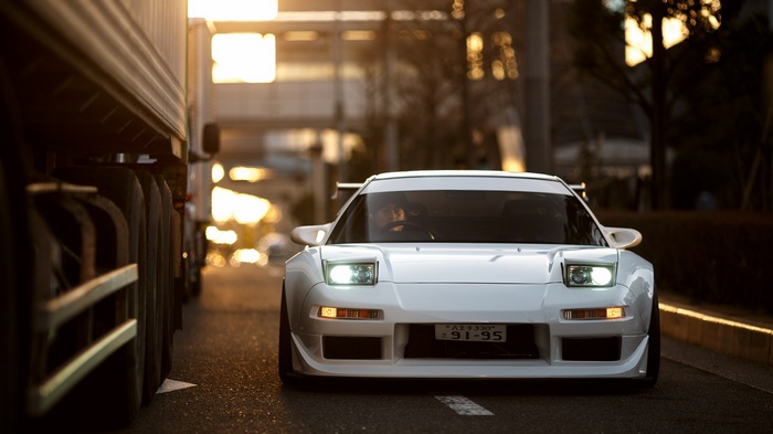 White Honda NSX driving on a street at sunset