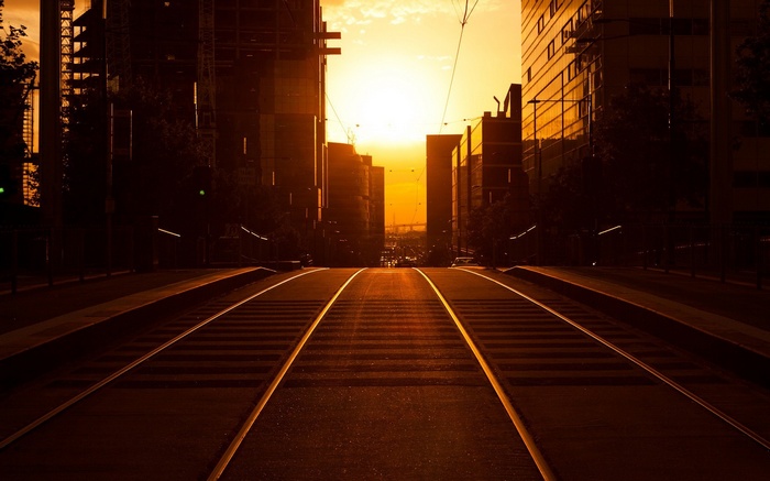 Tram tracks leading to the city at sunset