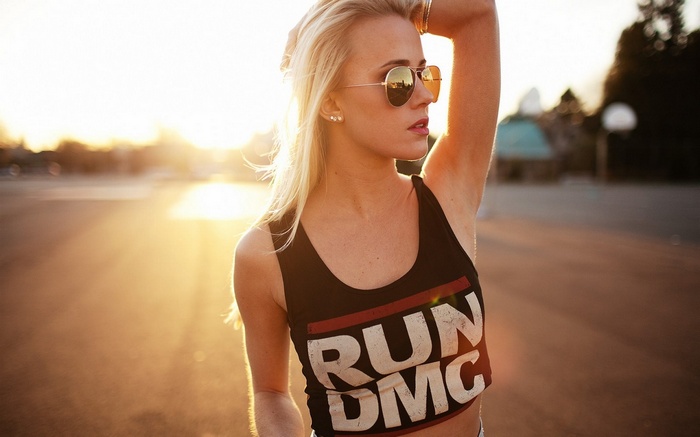 Woman wearing RUN DMC crop top and sunglasses at sunset