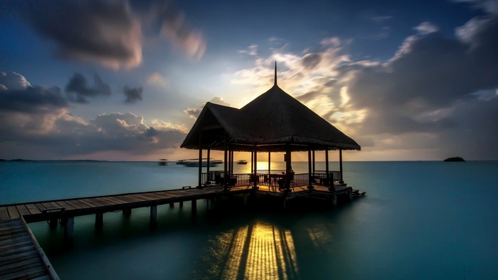 Sunset over the sea with a wooden pier and gazebo