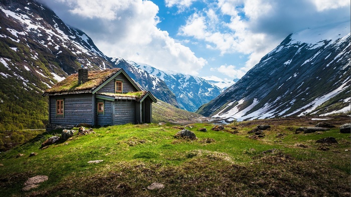 Wooden cabin in a Norwegian valley with snowy mountains