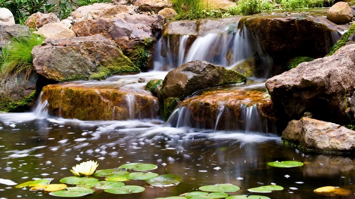 Waterfall cascading over rocks into a pond with water lilies