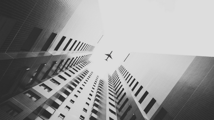 Monochrome view of buildings and an airplane