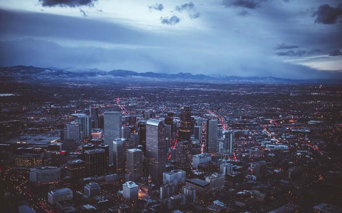 Aerial view of a city skyline at dusk with mountains in the background