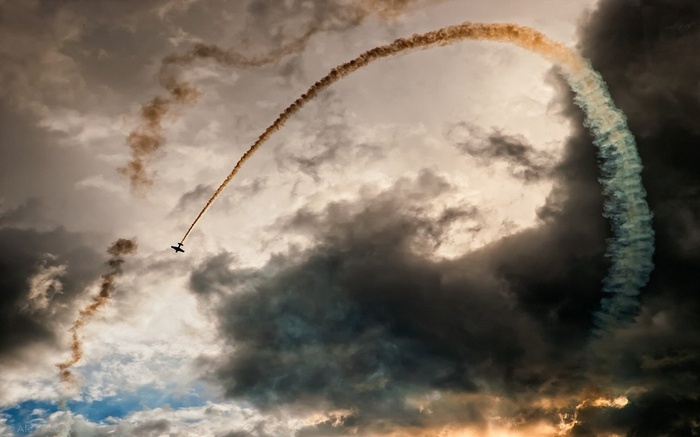 Airplane performing aerobatics with colored smoke trails
