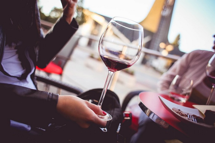 Woman holding a glass of red wine at a table