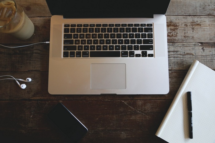 Laptop, headphones, and iced coffee on a wooden desk